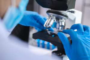 Scientist analyzing microscope slide at laboratory, technician examining a histological sample