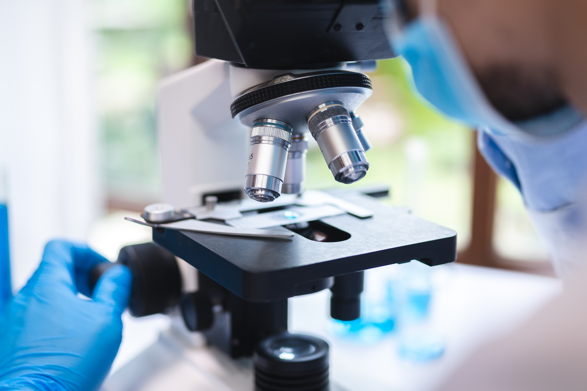 Scientist analyzing microscope slide at laboratory, technician examining a histological sample