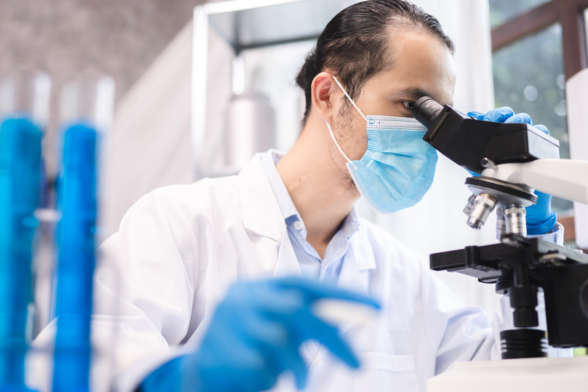 Scientist analyzing microscope slide at laboratory, technician examining a histological sample